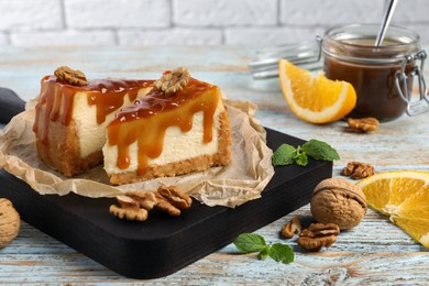 Photo of Pieces of delicious caramel cheesecake with walnuts and orange served on wooden table