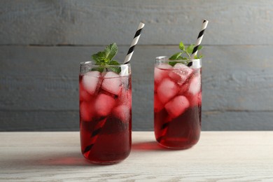 Photo of Delicious iced hibiscus tea with mint on white wooden table