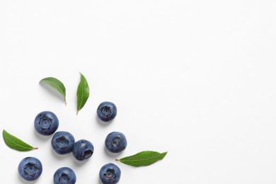 Photo of Tasty fresh blueberries with green leaves on white background, flat lay. Space for text