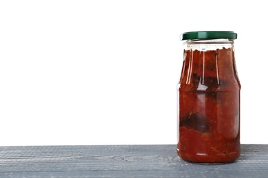 Photo of Jar of vegetable sauce on blue wooden table against white background. Pickled food