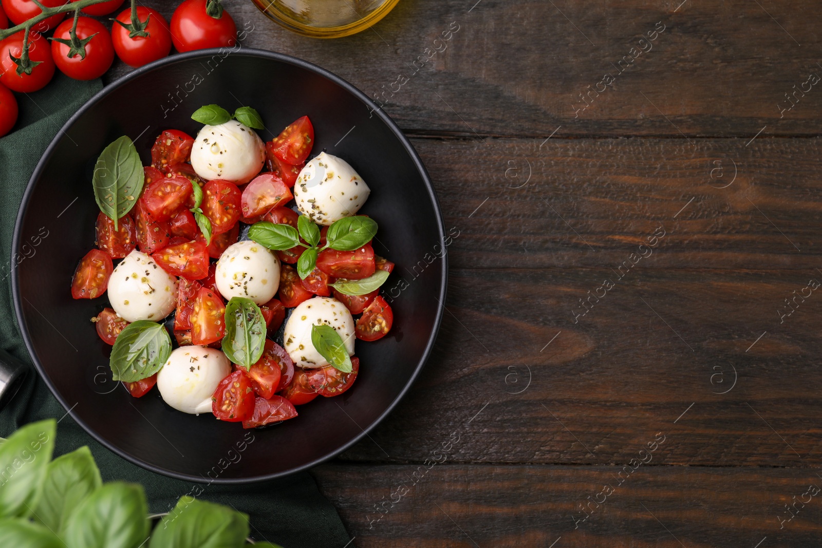 Photo of Tasty salad Caprese with tomatoes, mozzarella balls and basil on wooden table, flat lay. Space for text