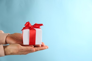 Photo of Woman holding gift box on light blue background,  space for text. Valentine's Day celebration