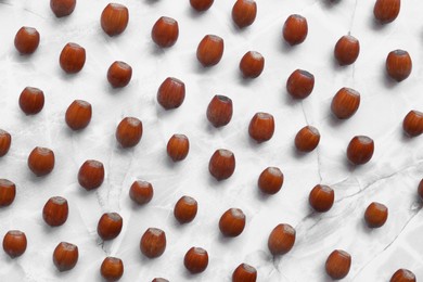 Tasty hazelnuts on light marble table, flat lay