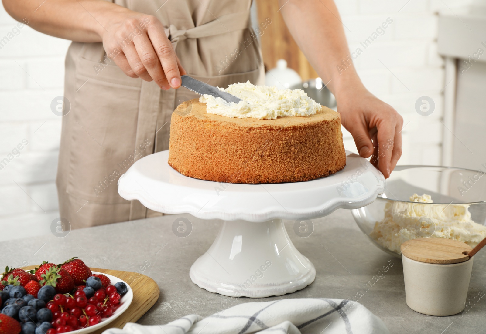 Photo of Woman decorating delicious cake with fresh cream at table indoors, closeup. Homemade pastry