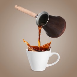 Pouring freshly brewed aromatic coffee from turkish pot into cup. Objects in air on dark dusty beige background