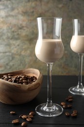 Photo of Coffee cream liqueur in glasses and beans on black wooden table