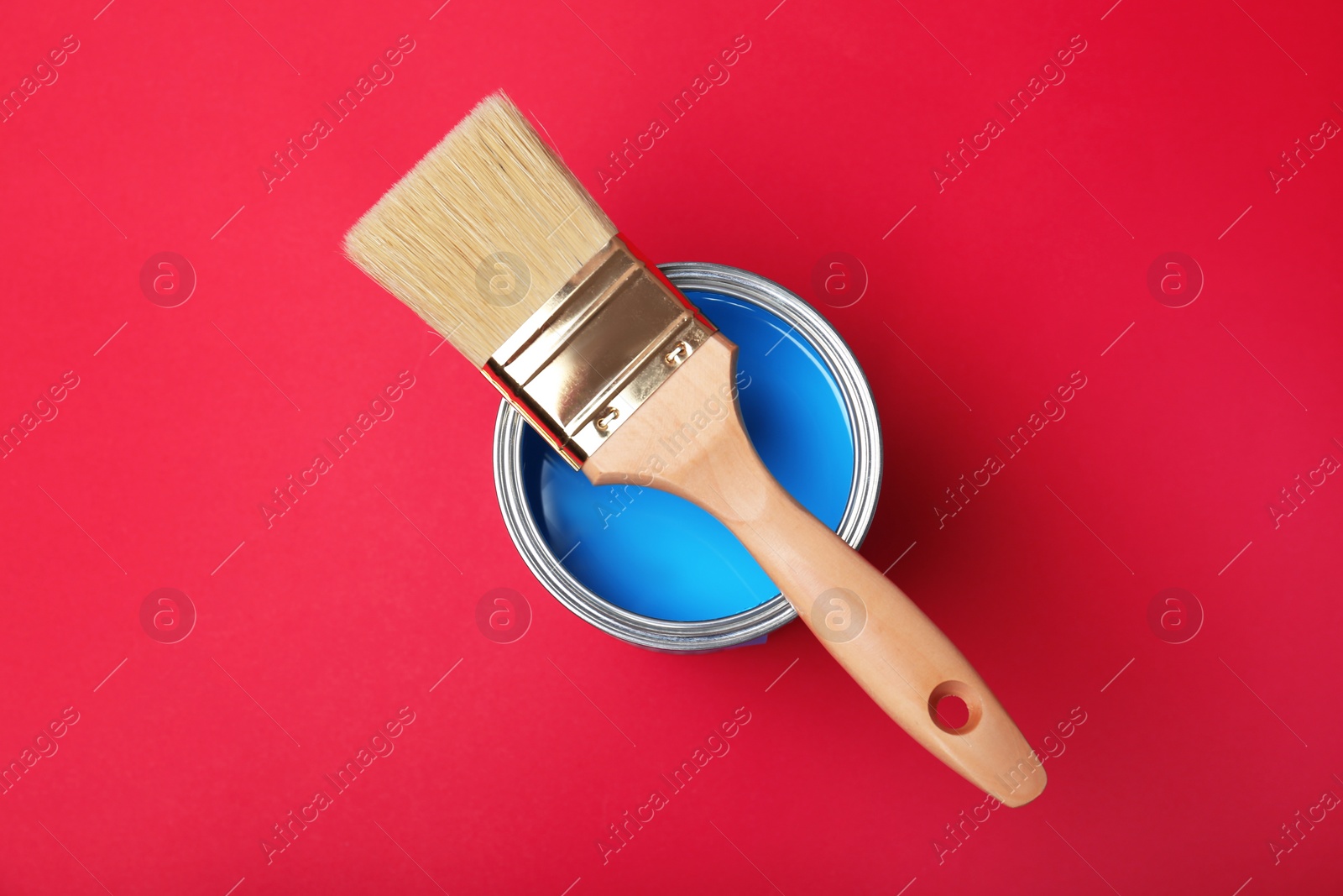 Photo of Paint can and brush on red background, top view