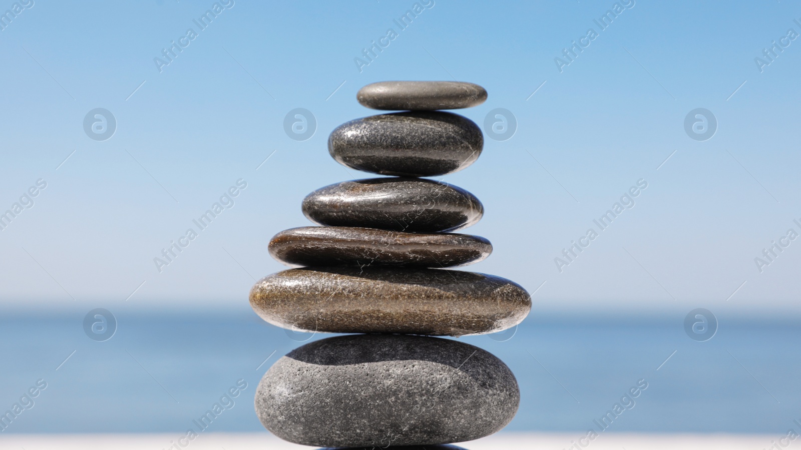 Photo of Stack of stones against blurred seascape, closeup. Zen concept