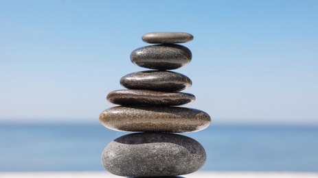 Photo of Stack of stones against blurred seascape, closeup. Zen concept