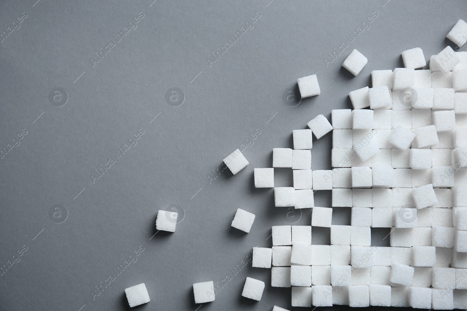 Photo of Refined sugar cubes on grey background, top view