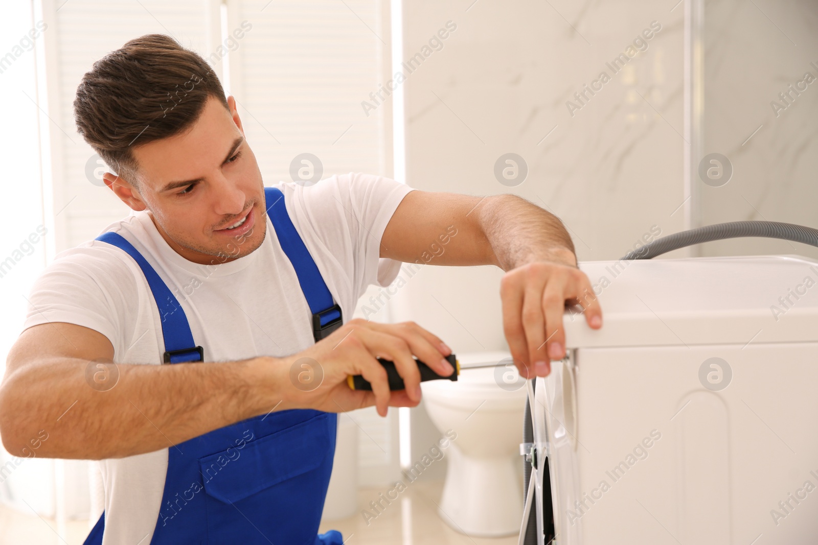 Photo of Professional plumber repairing washing machine in bathroom