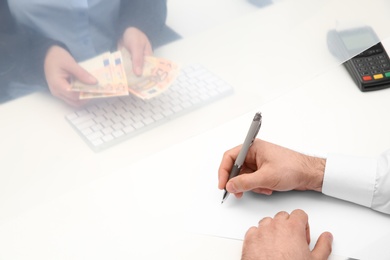 Man filling blank at cash department window, closeup