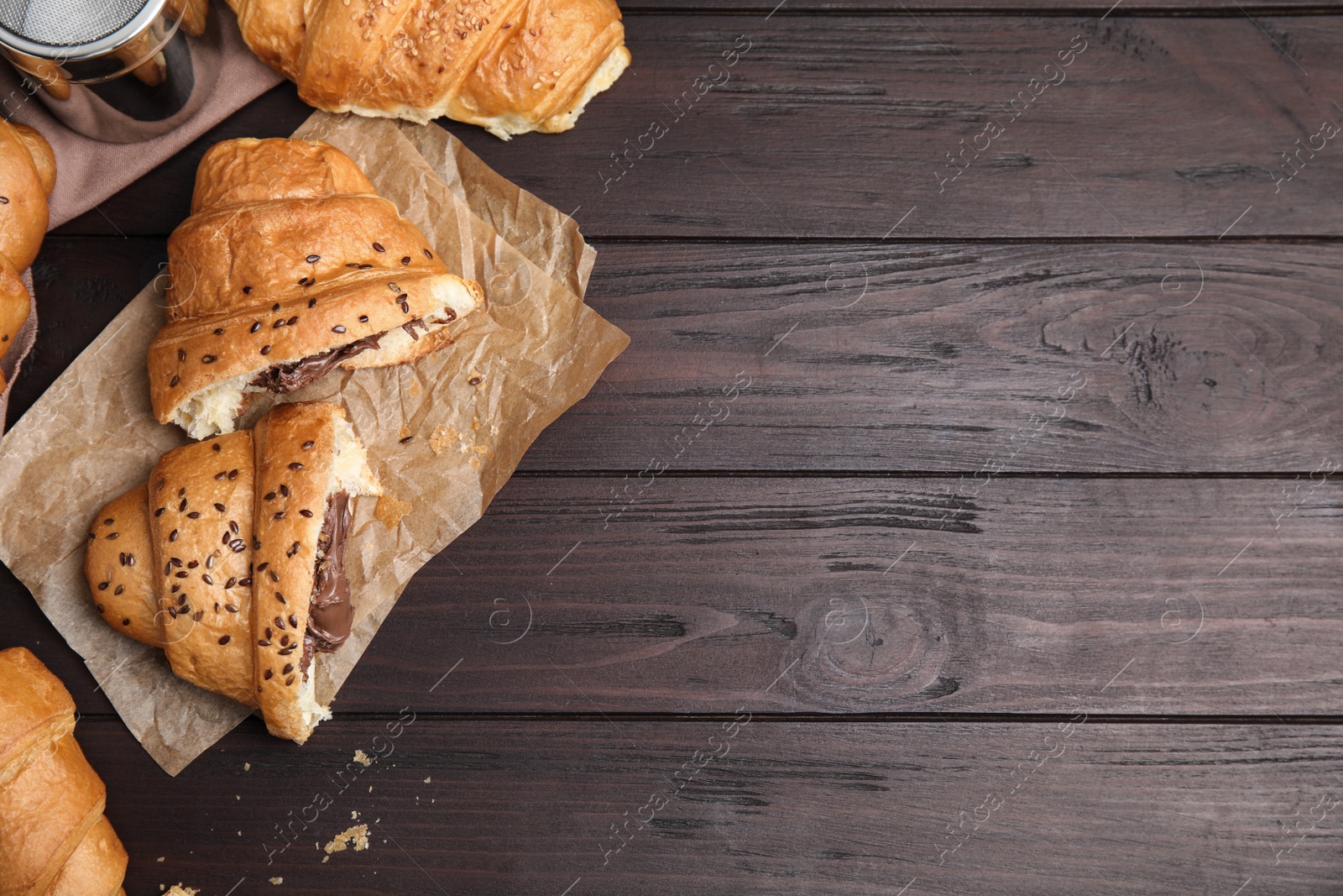 Photo of Fresh croissants with chocolate on wooden table, flat lay. Space for text