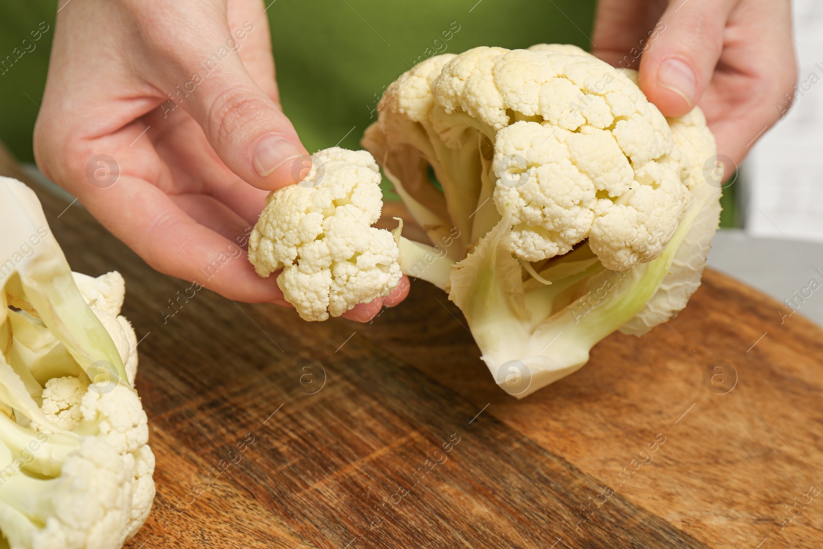 Photo of Woman holding fresh cauliflower above wooden board, closeup