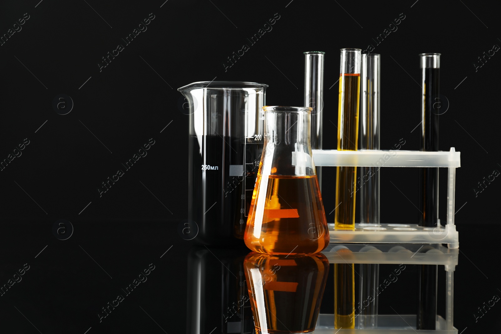 Photo of Laboratory glassware with different types of oil on black background. Space for text