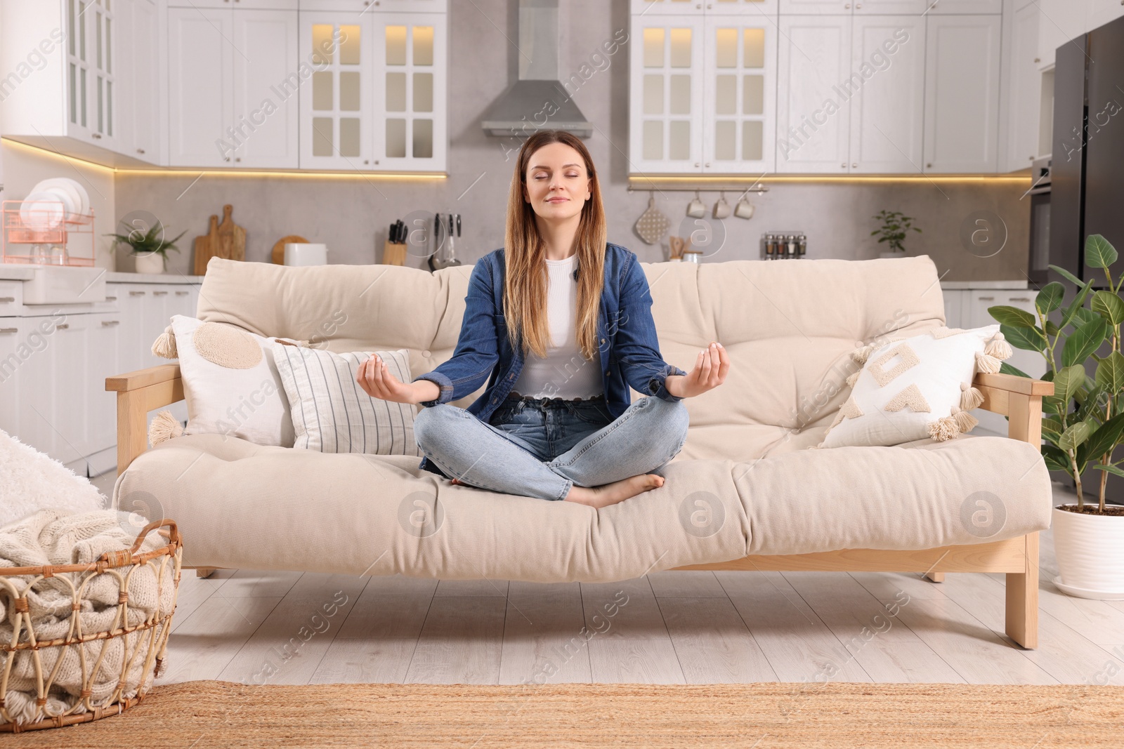 Photo of Woman meditating on sofa at home. Harmony and zen