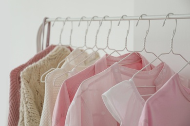 Photo of Rack with stylish clothes near white wall, closeup
