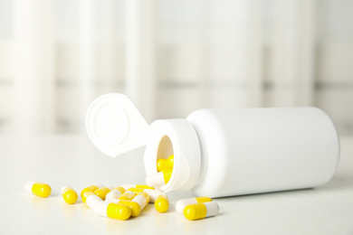 Bottle with vitamin pills on white table