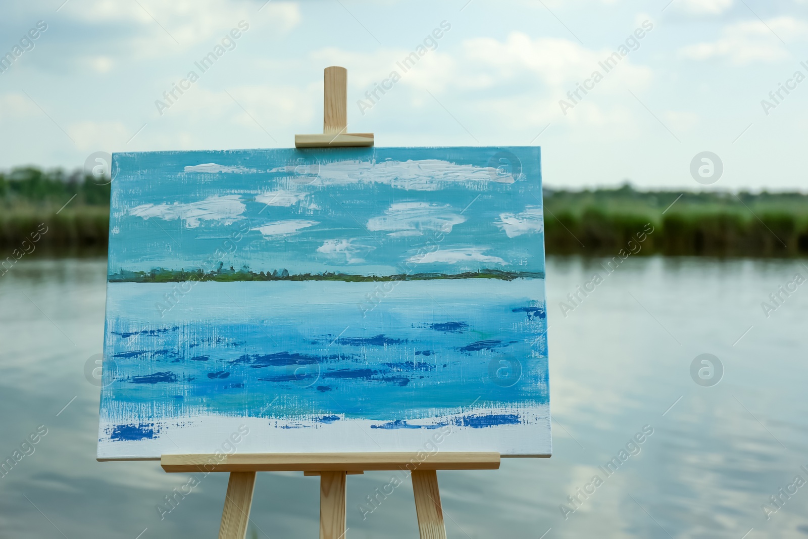 Photo of Wooden easel with unfinished painting near lake