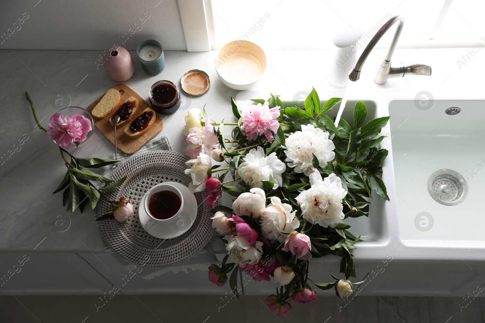 Photo of Beautiful peonies and breakfast on kitchen counter, above view