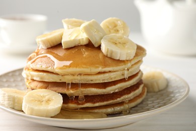 Photo of Delicious pancakes with bananas, honey and butter on white wooden table, closeup