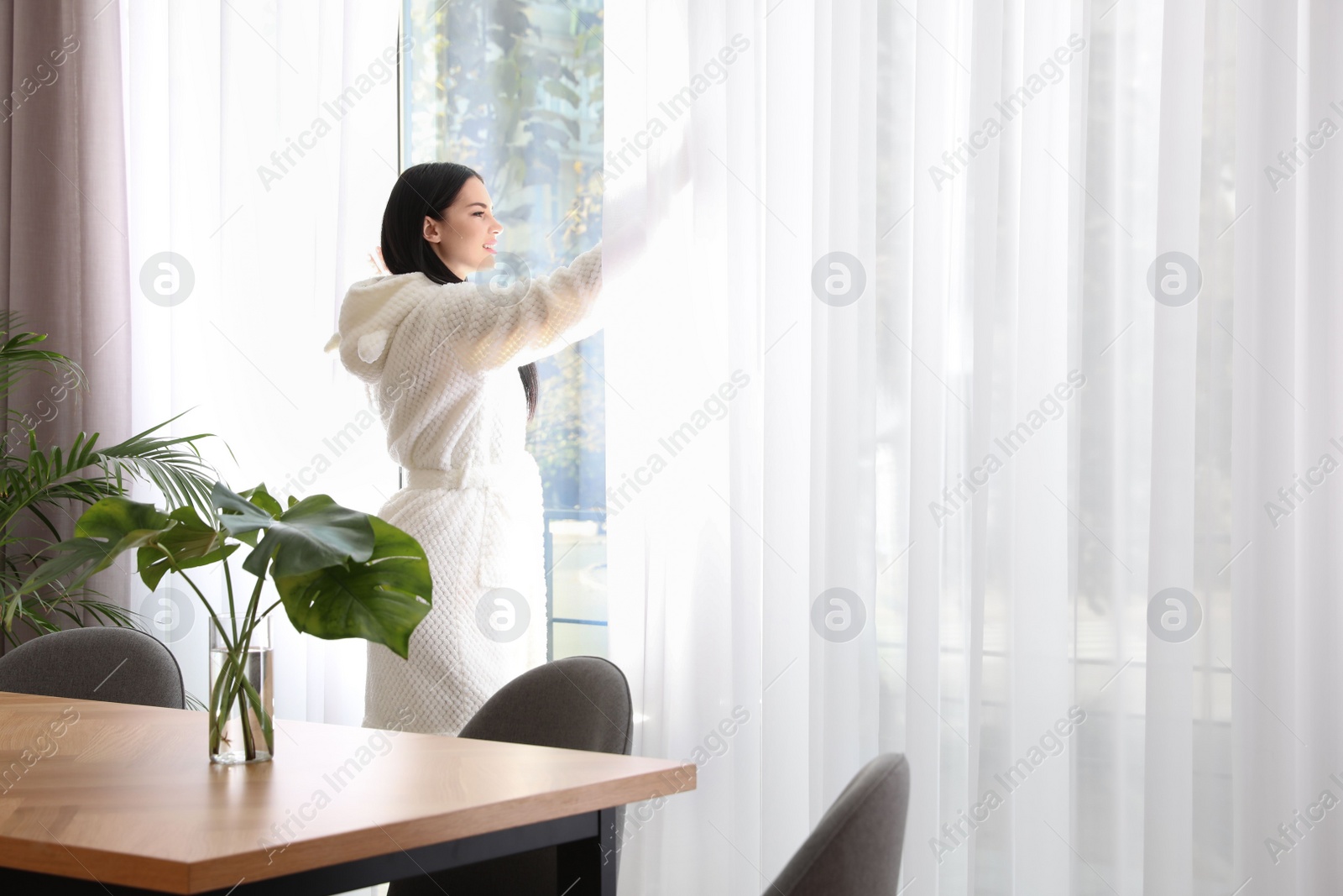 Photo of Woman near window in room decorated with plants. Home design ideas