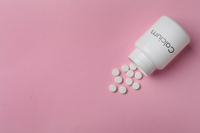 Calcium supplement. Bottles with pills on pink background, flat lay and space for text