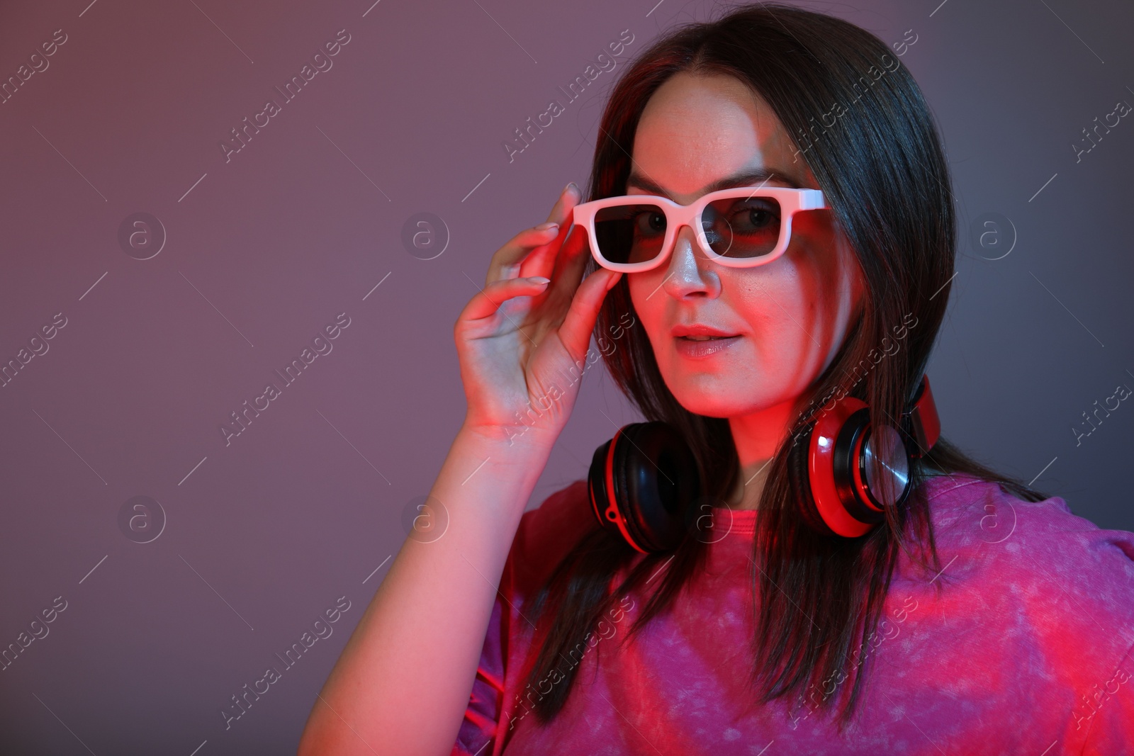 Photo of Stylish woman with headphones wearing sunglasses on color background, space for text