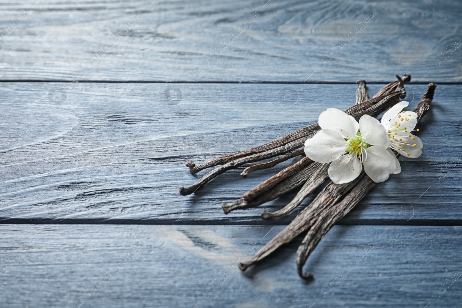 Photo of Vanilla sticks and flowers on wooden background