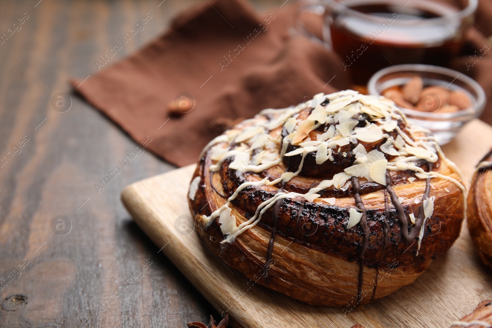 Photo of Sweet bun. Delicious roll with toppings and nuts on wooden table, closeup. Space for text