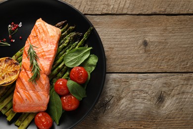 Photo of Tasty grilled salmon with tomatoes, asparagus and spices on wooden table, top view. Space for text