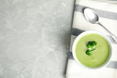 Photo of Delicious broccoli cream soup served on grey marble table, top view. Space for text