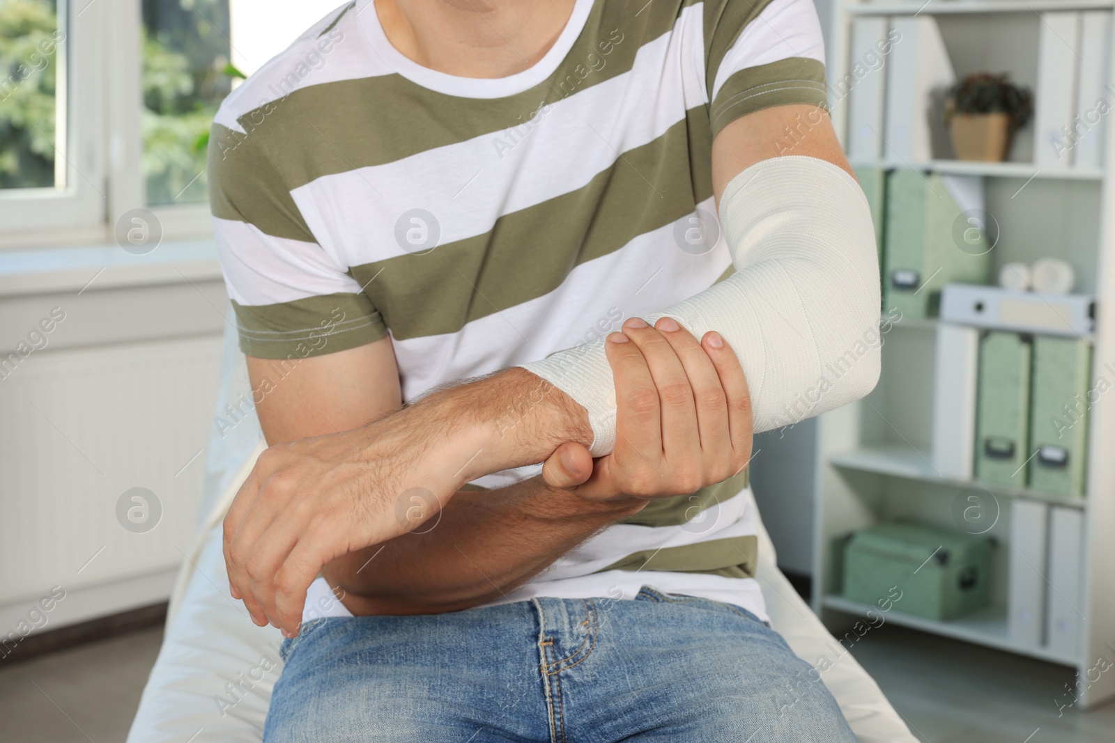 Photo of Man with arm wrapped in medical bandage at hospital, closeup