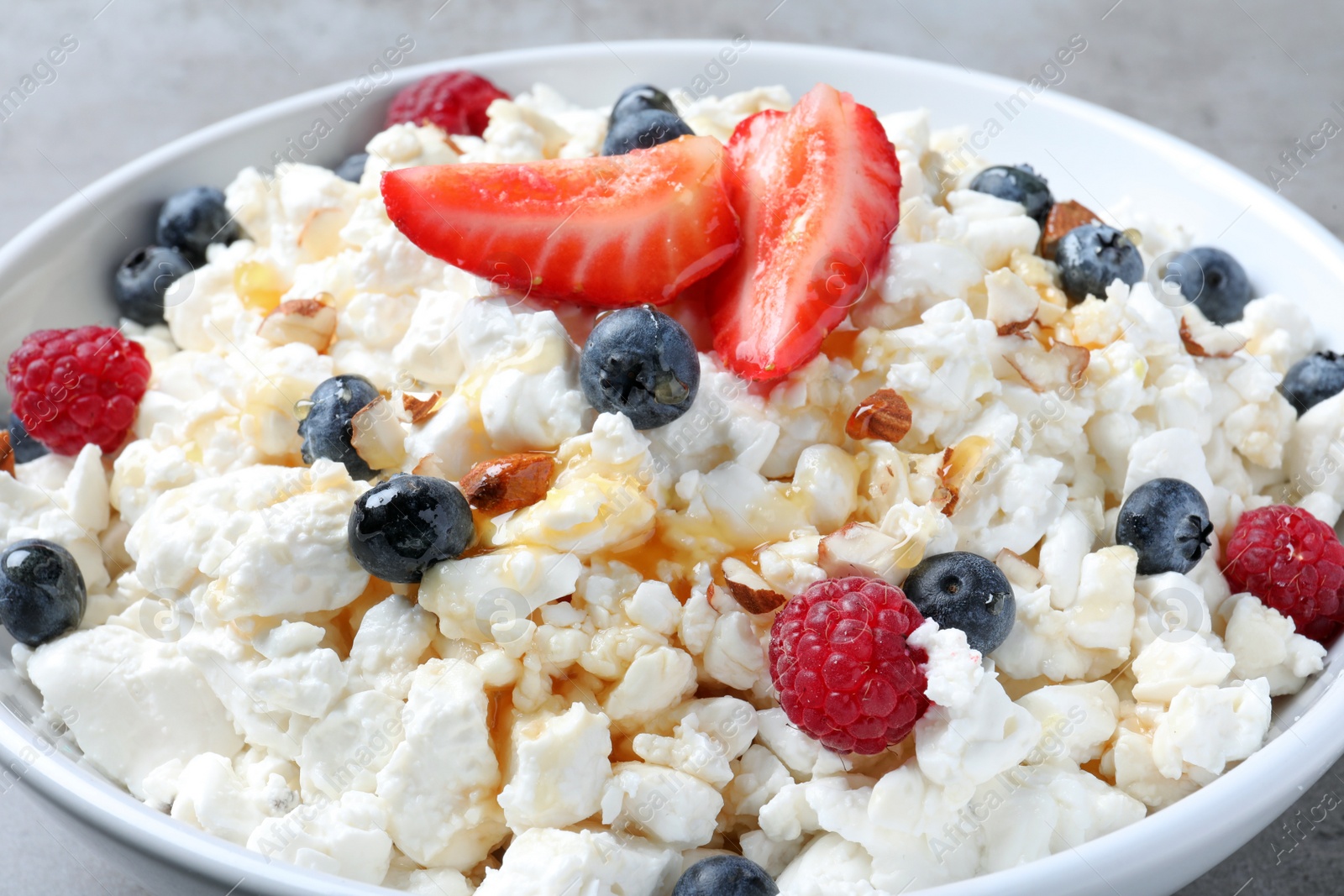 Photo of Delicious cottage cheese with fresh berries in bowl, closeup. Tasty breakfast