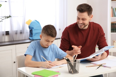 Photo of Dad helping his son with homework in room