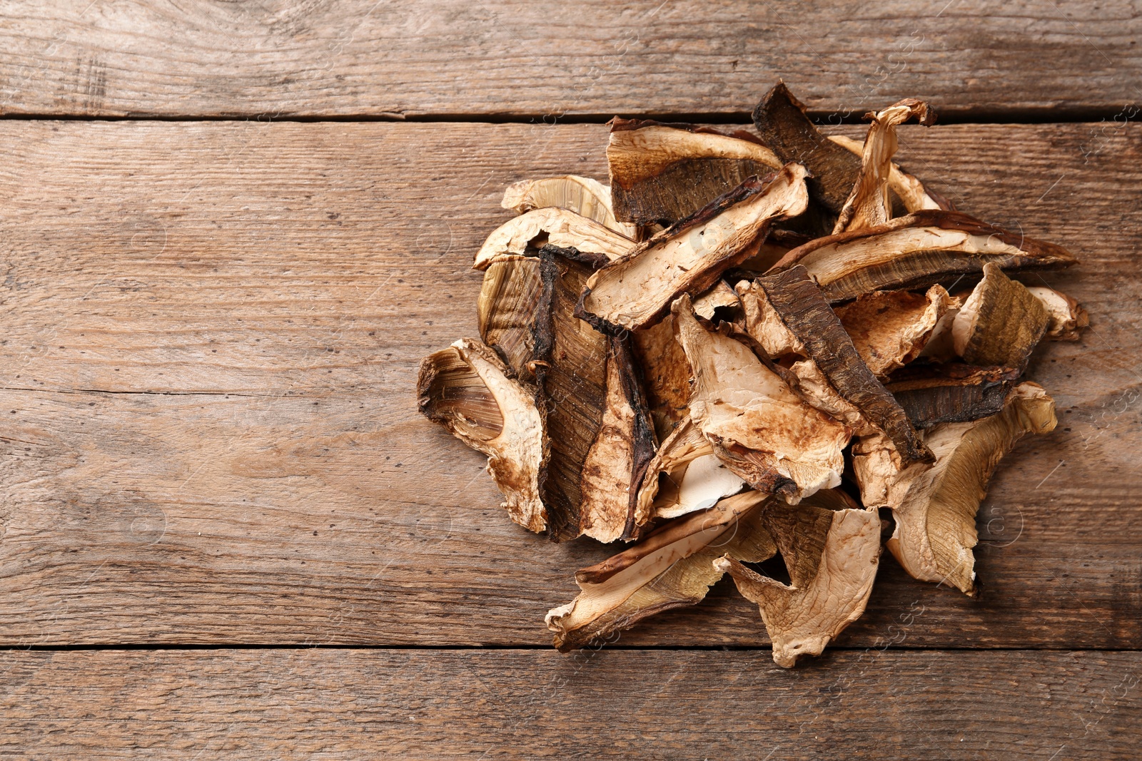 Photo of Delicious dried mushrooms on wooden background, top view with space for text