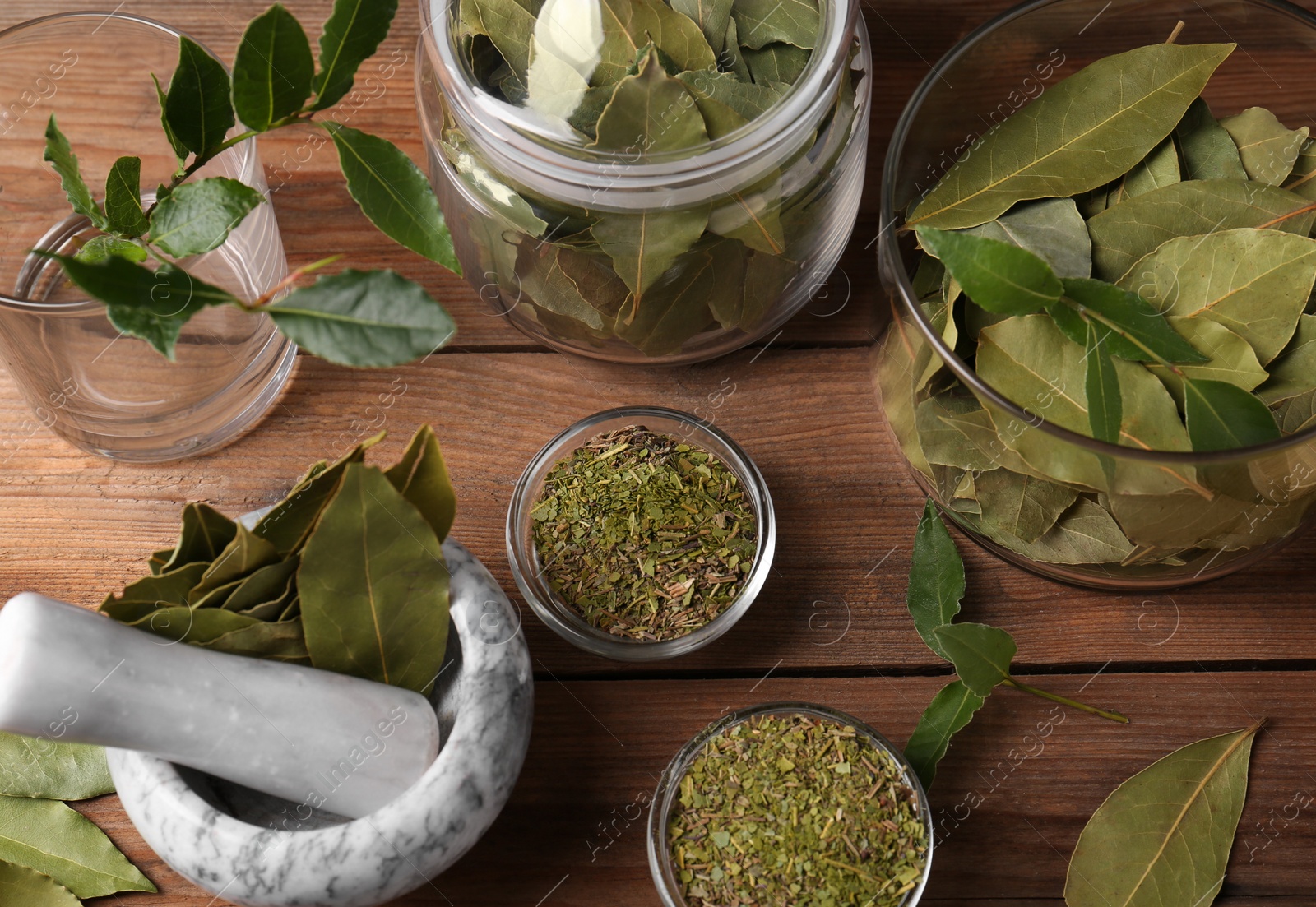 Photo of Whole and ground aromatic bay leaves on wooden table, flat lay