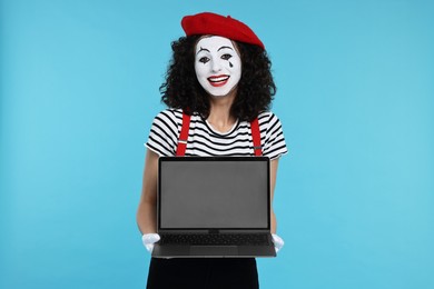 Photo of Funny mine with laptop posing on light blue background