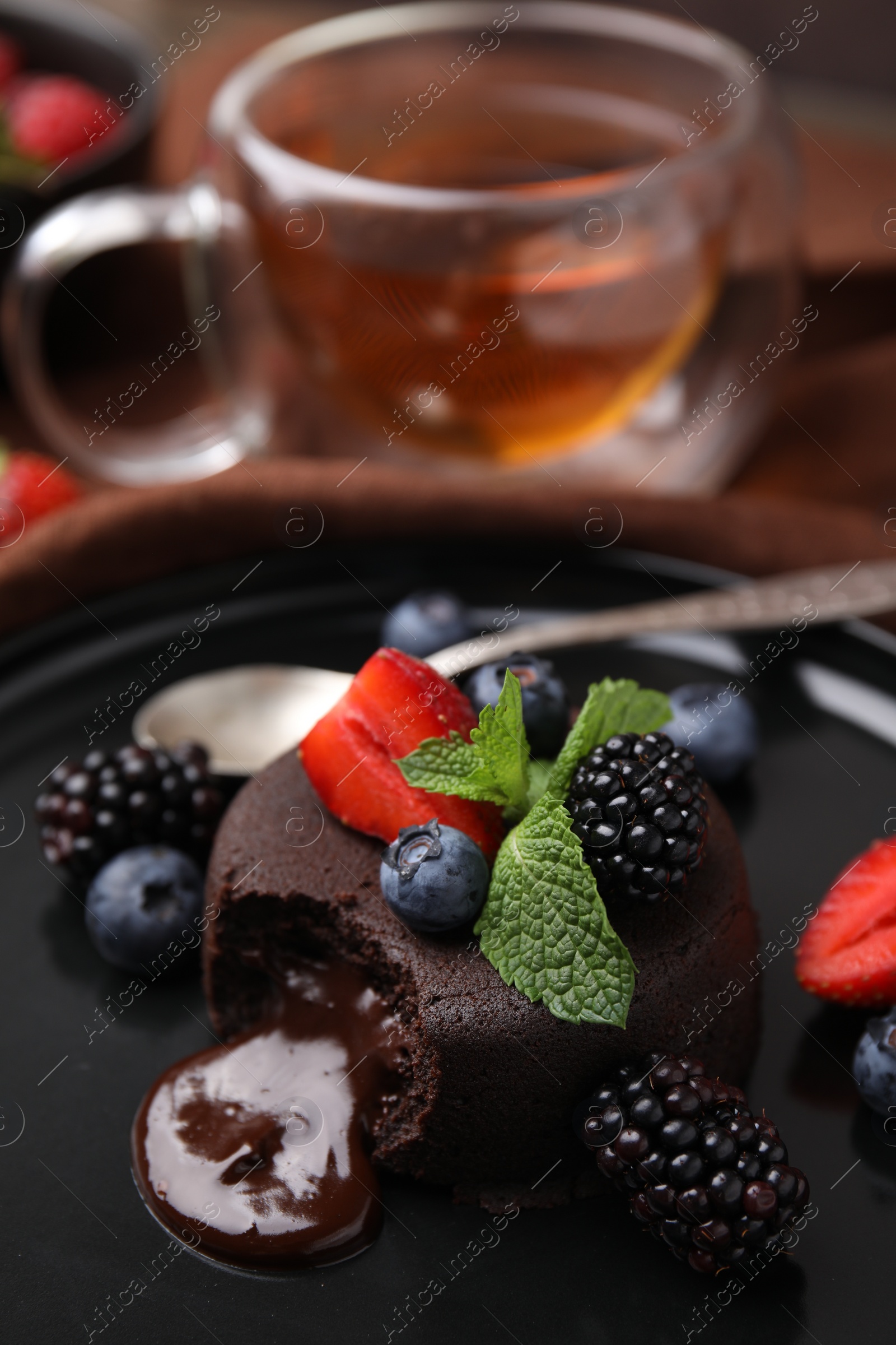 Photo of Delicious chocolate fondant, berries and mint on plate, closeup