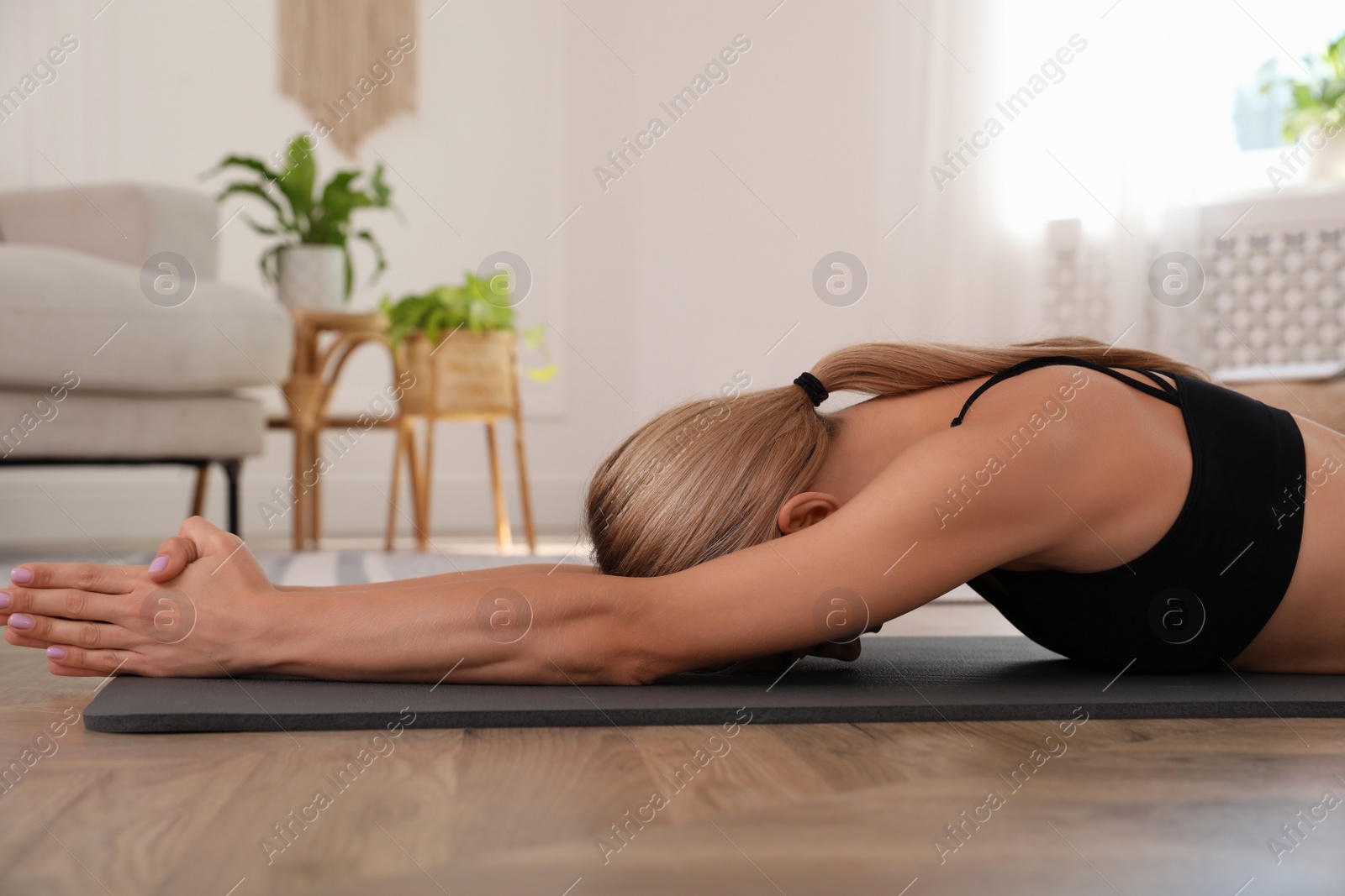 Photo of Woman practicing yoga in light room at home
