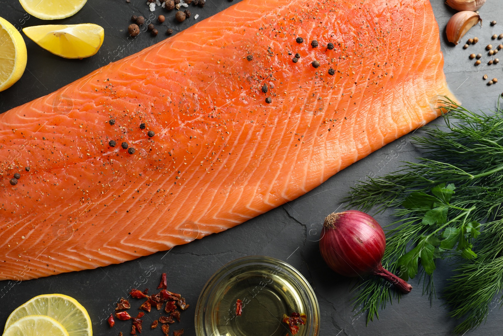 Photo of Fresh raw salmon and ingredients for marinade on black table, flat lay