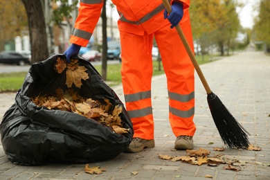 Worker cleaning street from fallen leaves on autumn day, closeup