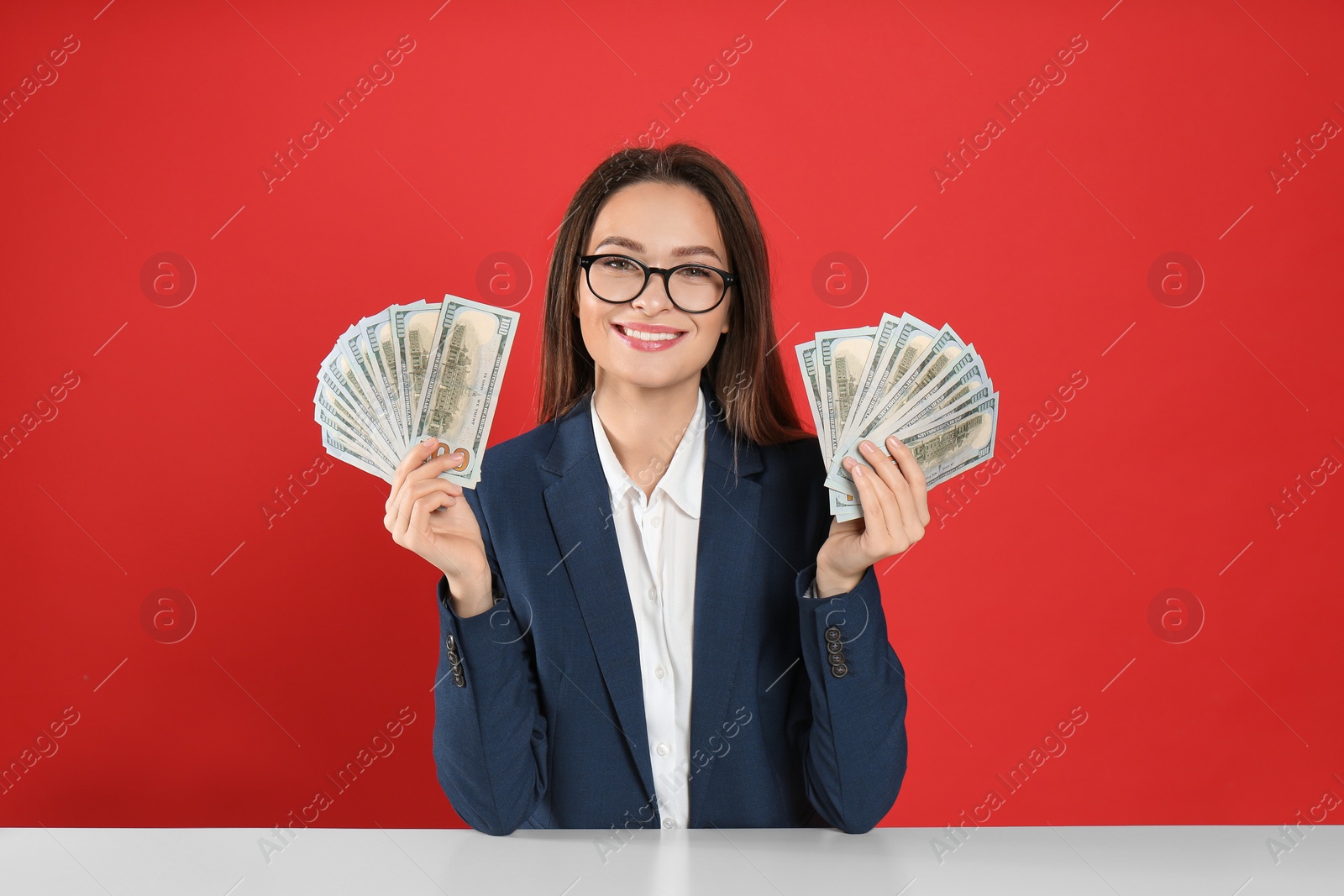 Photo of Young woman with money at table on crimson background