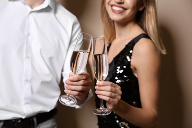 Photo of Happy couple with glasses of champagne on color background, closeup