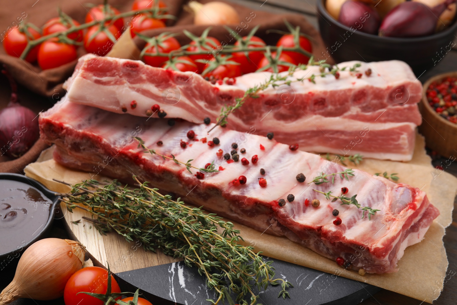 Photo of Raw pork ribs with thyme and peppercorns on table, closeup