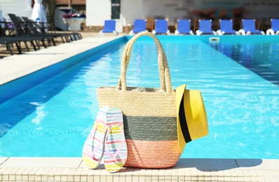 Bag with beach accessories near swimming pool on sunny day