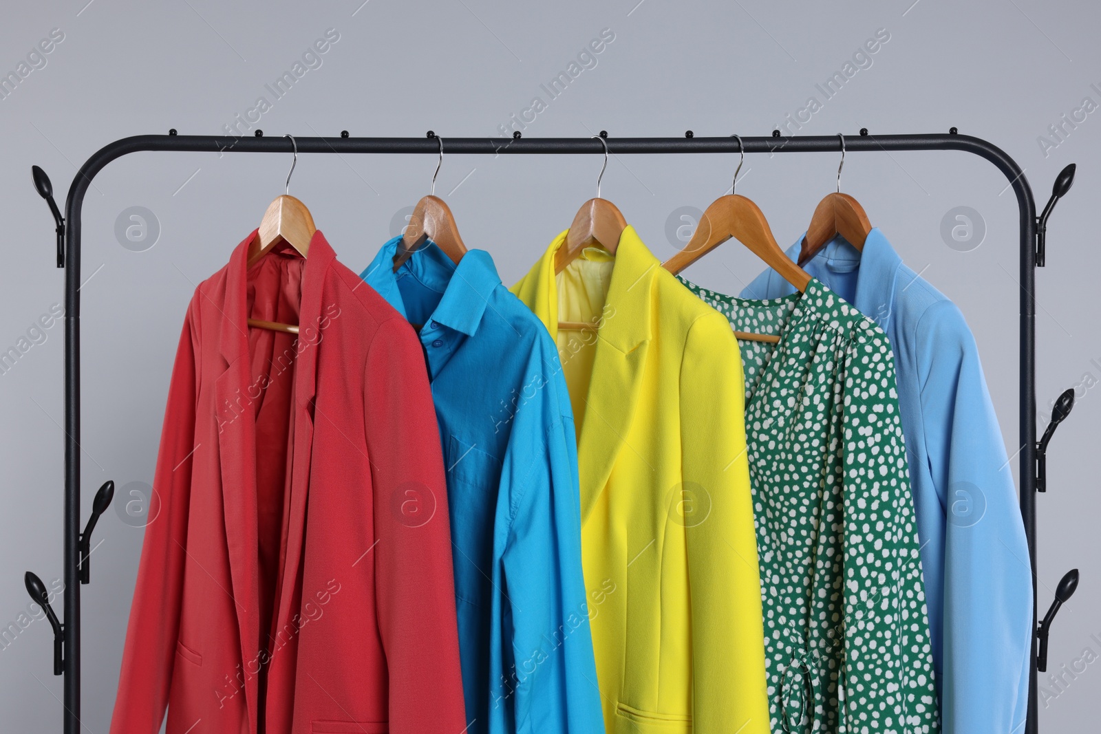 Photo of Rack with stylish women`s clothes on wooden hangers against light grey background