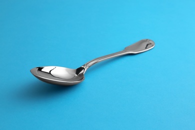 Photo of Clean empty tea spoon on blue background