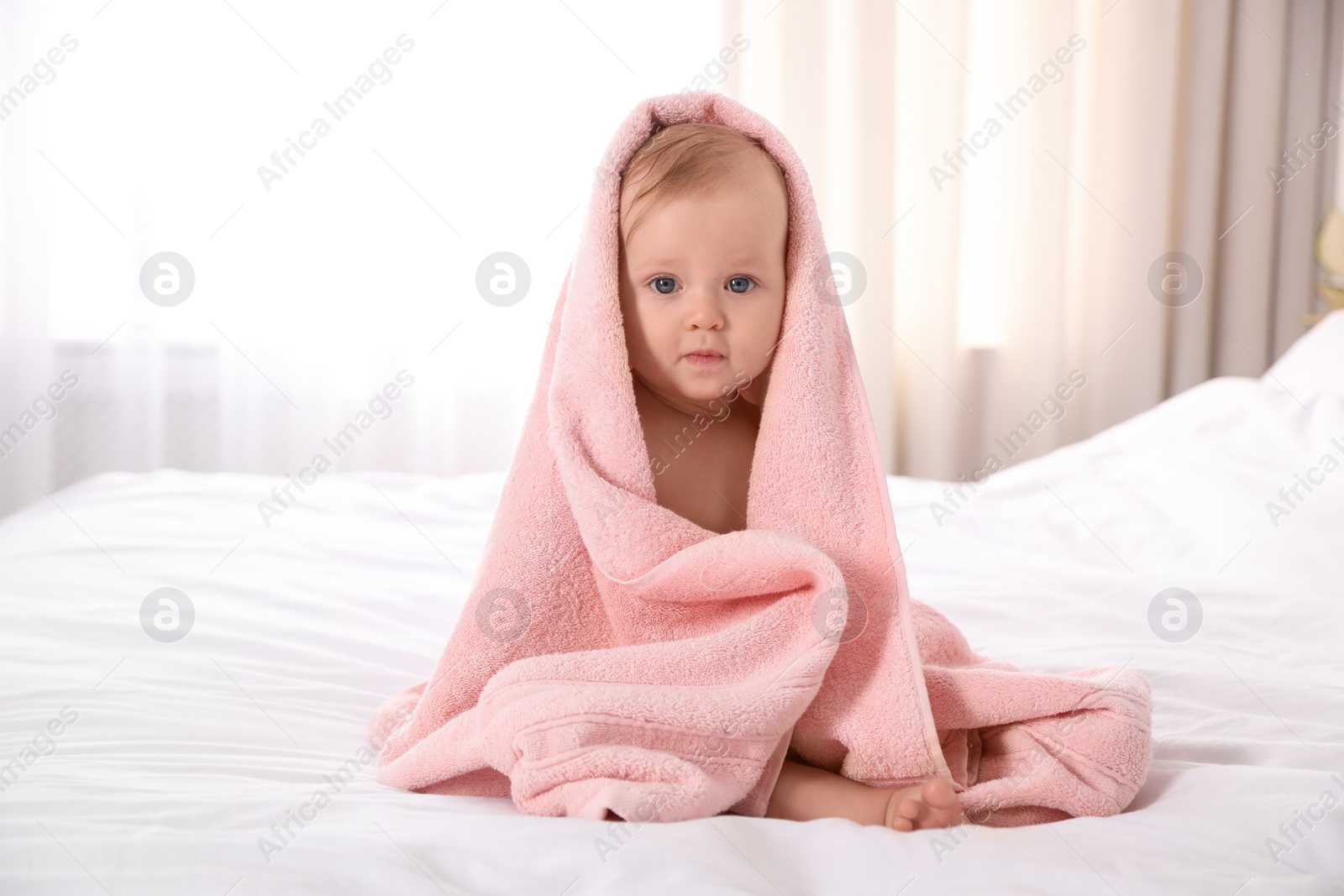 Photo of Cute little baby with soft pink towel on bed after bath
