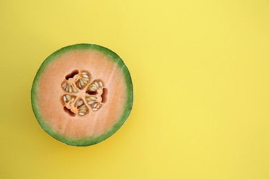 Photo of Half of fresh ripe cantaloupe melon on yellow background, top view. Space for text